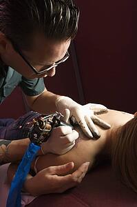 Tattoo artist tattooing woman