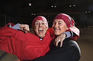 Women hockey players excited and posing with helmets off on ice rink