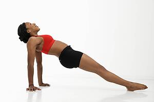 Profile of African American young adult woman exercising in strength training position.