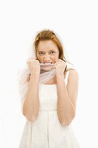 Portrait of Caucasian bride biting her veil.