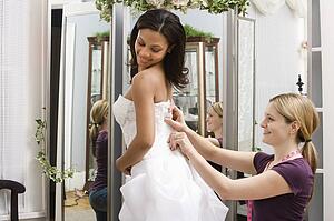 Seamstress helping bride in bridal shop.