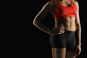Torso of muscular African American woman wearing athletic apparel with hand on hip.