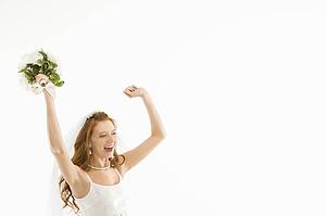 Bride holding bouquet and raising arms
