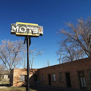 Rundown motel building with blue sky in background.