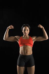 Muscular African American woman wearing athletic apparel with biceps flexed.