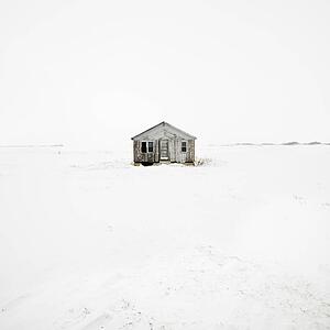 Abandoned house in snow covered landscape.