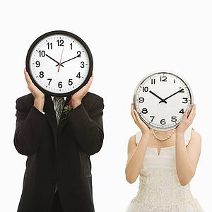 Portrait of groom and bride with clocks covering their faces. 