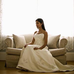Portrait of an Indian bride sitting on a love seat.