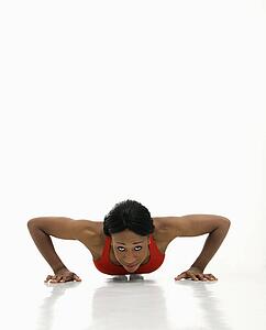 African American young adult woman doing push up and looking at viewer.