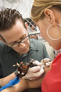 Tattoo artist tattooing woman