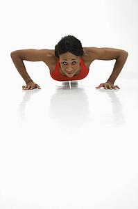African American young adult woman doing push up and looking at viewer.