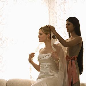 Bridesmaid placing veil on bride