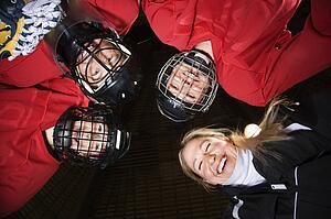 Low angle of female hockey players in huddle with coach smiling.