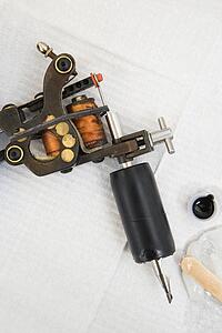 Close up shot of tattoo gun and black ink.