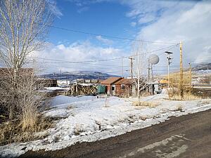 House with firewood with dirt road in foreground