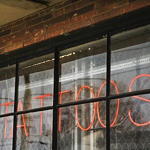 Neon sign in window for tattoos and body piercing.