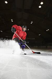 Woman hockey player sliding kicking up ice