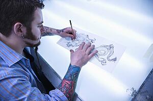 Tattoo artist drawing tattoo on light table