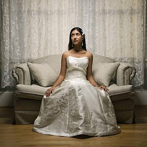 Portrait of an Indian bride sitting on a love seat.