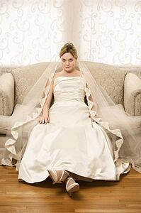 Caucasian bride slouching in love seat.