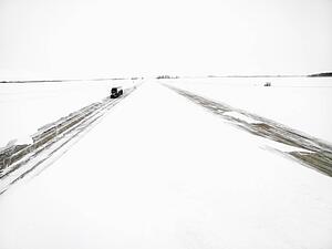 Transfer truck driving down highway in a winter storm.