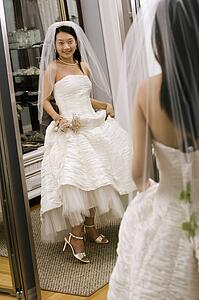 Asian bride admiring shoes in mirror.