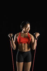 Smiling African American young adult woman exercising with resistance tube.