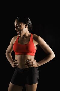 Smiling African American young adult woman in athletic apparel with hands on hips.
