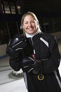 Female hockey coach in uniform standing smiling.