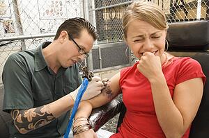 Tattoo artist tattooing woman