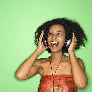 African-American woman listening to music through headphones.