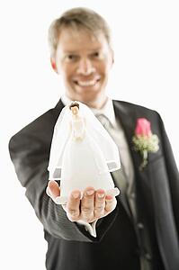 Groom holding out bride figurine in palm of his hand