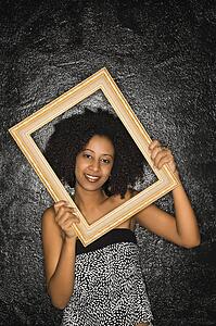 African-American woman holding frame over her face.
