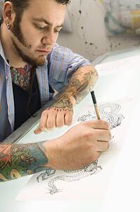Tattoo artist drawing tattoo on light table