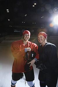Women hockey players in uniform posing with helmets off on ice rink