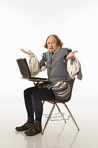 William Shakespeare in period clothing sitting in school desk with laptop and shrugging at viewer