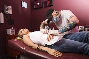 Man giving young woman naval piercing.
