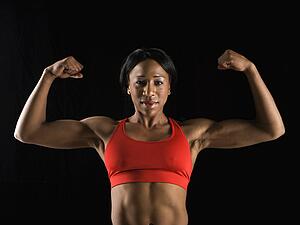 Muscular African American woman looking at viewer with biceps flexed.