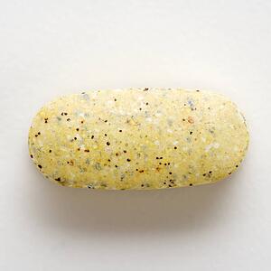 Close up of brown speckled caplet against white background.