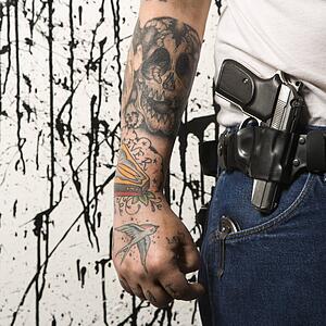 Tattooed man wearing holster with gun