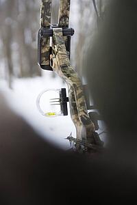 Camouflage bow and arrow with blurred foreground.