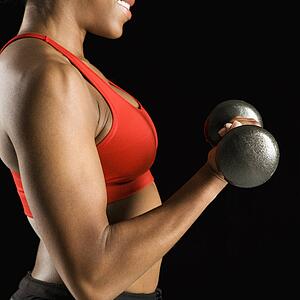 Torso of African American young adult woman lifting dumbbell.