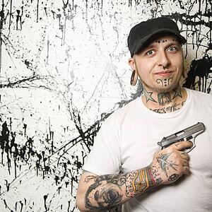 Tattooed man holding gun.