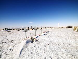 Snow covered graveyard with clear blue sky in background.
