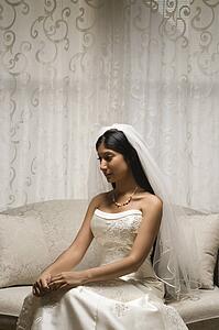 Portrait of an Indian bride sitting on a love seat.
