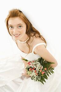 Portrait of a Caucasian bride holding bouquet.
