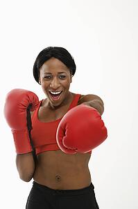 African American young adult woman wearing boxing goves throwing playful punch at viewer.