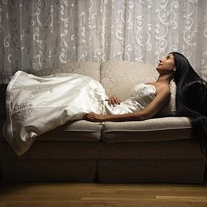 Portrait of an Indian bride lying on love seat.