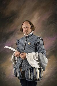 William Shakespeare in period clothing holding feather pen standing 