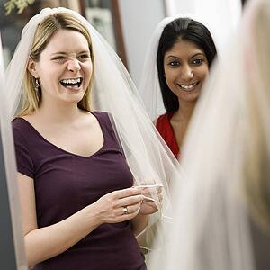 Indian woman and Caucasian woman trying on veils and looking in mirror.